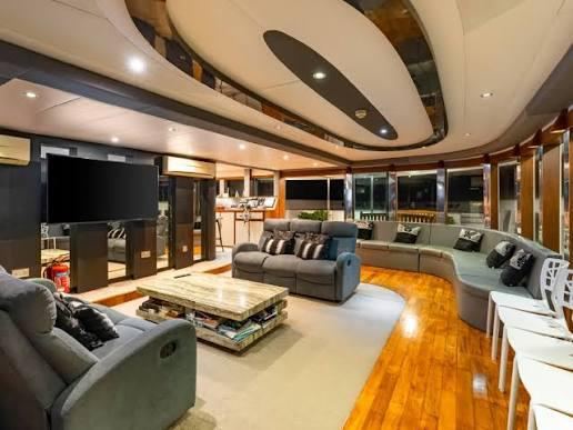 Main-deck lounge: Big sofas, a Smart TV for reviewing the day’s dive footage, and a shelf of books.